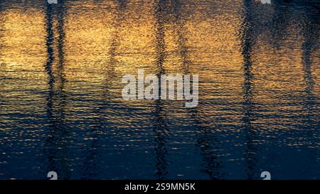 Goldenes Sonnenlicht leuchtet sanft über das wellige Wasser und erzeugt ruhige Reflexe. Eine friedliche und natürliche abstrakte Szene, die Ruhe und Wärme in sich birgt Stockfoto