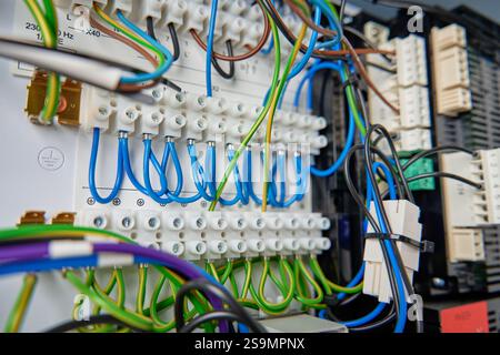 Farbenfrohe Drähte und Komponenten, die mit dem Anschlussblock im Verteilerkasten verbunden sind. Elektrische Leiterplatte mit Verkabelung und Anschlüssen Stockfoto