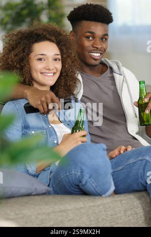 Porträt eines jungen Paares, das auf dem Sofa fernsieht Stockfoto
