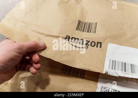 Nahaufnahme Einer Person, die ein Amazon-Paket öffnet und die Begeisterung und Erwartung von Online-Einkäufen und Lieferungen hervorhebt. Januar, Stockfoto