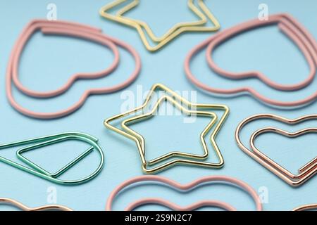 Verschiedene Büroklammern auf hellblauem Hintergrund, Nahaufnahme Stockfoto