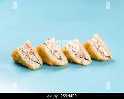 Heiße Tempura onigirazu mit Lachsmousse auf blauem Hintergrund. Onigirazu ist ein Sushi-Sandwich oder Burgerbrötchen. Stockfoto