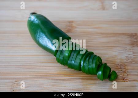 Grüner Jalapeno-Pfeffer, halb gehackt auf Holzschneidebrett. Stockfoto