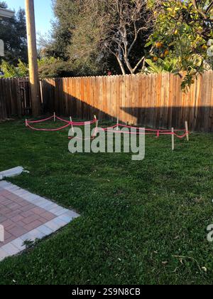 Rosafarbenes Klebeband und Holzpfähle markieren einen Garten im Garten Stockfoto