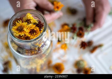 Glasgefäß gefüllt mit getrockneten Blumen und Hände arbeiten im Hintergrund Stockfoto