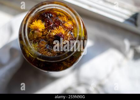 Blick von oben auf das Glas gefüllt mit getrockneten Ringelblumen und Olivenöl Stockfoto
