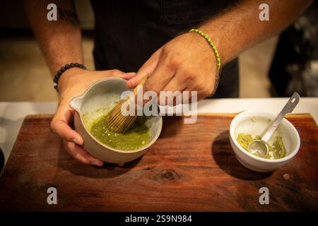 Barista, der Matcha-Tee in einer traditionellen Schüssel verquirlt Stockfoto