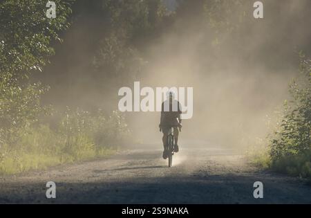 Mountainbiker auf einer unbefestigten Straße während der goldenen Stunde in einem ruhigen Tal. Stockfoto