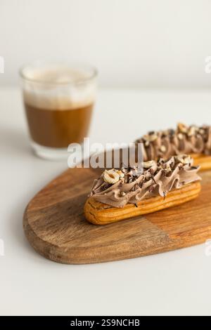 Französischer Eclair mit Schlagsahne und Haselnüssen auf Holztablett Stockfoto