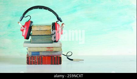 Hörbuchkonzept mit Buchreihe und Vintage-Kopfhörer auf blauem Hintergrund. Bildung, Inspiration, Entspannung, Literaturkonzept. Freier Kopierbereich. Stockfoto