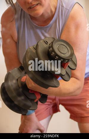 Frau, die während eines Krafttrainings eine verstellbare Hantel hebt Stockfoto