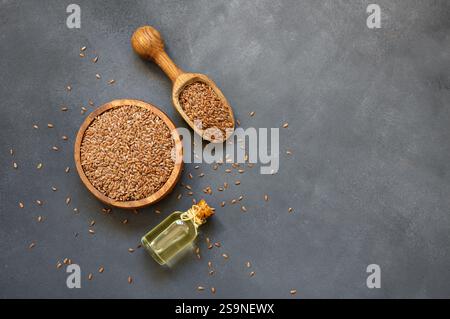 Haufen Leinsamen oder Leinsamen in Löffel oder Schüssel mit Glas Leinsamen Öl auf rustikalem Hintergrund. Leinsamen oder Leinöl Ballaststoffe Hintergrund Stockfoto