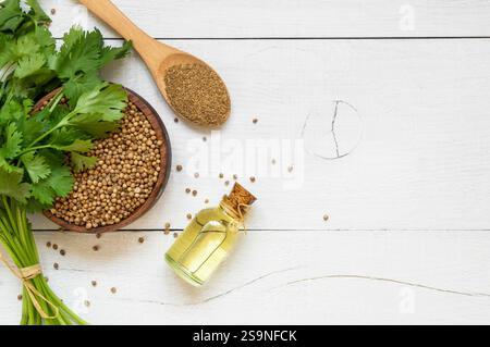 Glasflasche mit ätherischem Korianderöl mit Korianderpulver und frischen Korianderblättern auf rustikalem Tisch, Aromatherapie Massageöl Konzept ( coriandrum Stockfoto