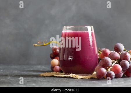 Glas aus schwarzem oder rotem Traubenfrucht-Kompott mit frischen Trauben, Bio-Obst-Kaltgetränk-Konzept, Originalfarbe Stockfoto