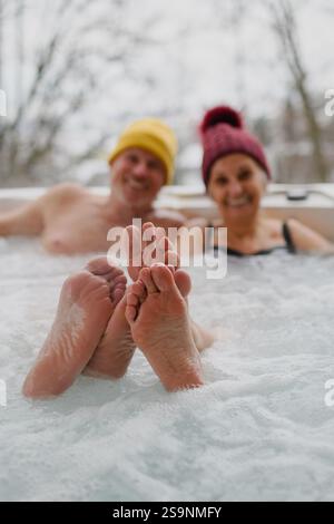 Schließen Sie sich den Füßen eines Seniorenpaares an, das an kalten Wintertagen im Wannen-Whirlpool badete. Stockfoto