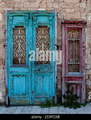 Alte, bunt bemalte Holztüren wurden von einem Gebäude entfernt und liegen an einer Mauer in Jaffa, Israel. Stockfoto