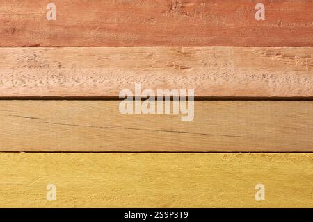 Nahaufnahme mehrerer horizontal gestapelter Holzdielen mit verschiedenen Farben, rötlich braun bis hellgelb Stockfoto