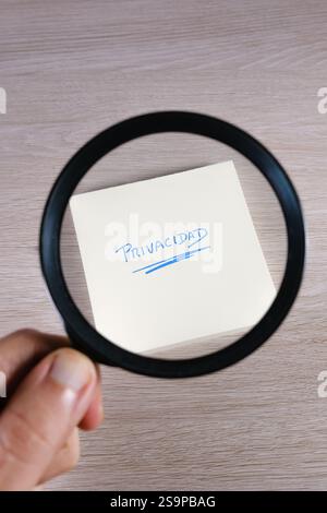 Vergrößerungsglas mit Fokus auf das Wort Privatsphäre, das auf einer Haftnotiz geschrieben ist Stockfoto