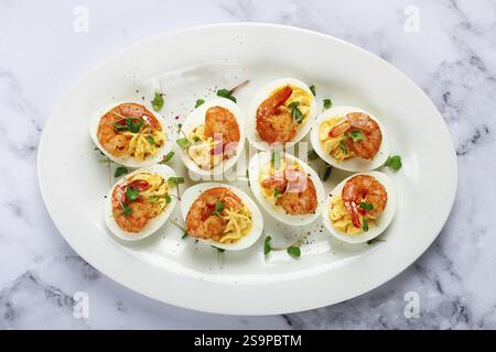 Gekochte Eier mit Eigelb gefüllt und mit Mayonnaise gewürzt, gefüllte Eier mit Garnelen, auf einem weißen Teller, selektiver Fokus, Nahaufnahme, ohne Menschen Stockfoto