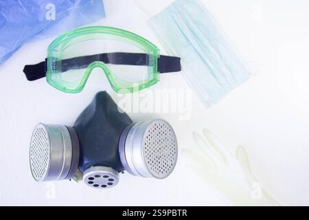 Schutzeinrichtung mit Schutzbrille, Maske und Handschuhen auf weißer Oberfläche Stockfoto