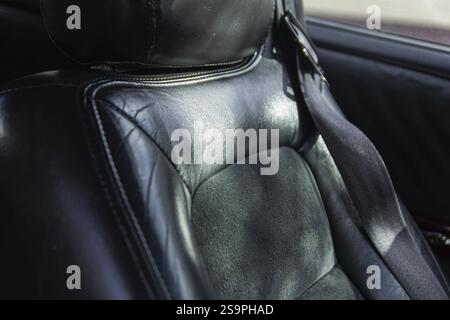 Nahaufnahme des schwarzen Ledersitzes im Auto mit Textur und Sonnenlicht Stockfoto