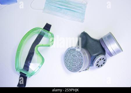 Grüne Schutzbrille, Gasmaske und chirurgische Maske auf weißer Oberfläche Stockfoto
