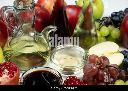 Verschiedene Arten von Essig Apfel, Balsamico, Wein und Granatapfel in Essigschalen unter Früchten. Stockfoto