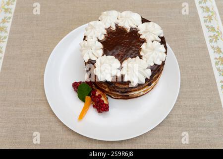 Ein wunderschön gestaltetes Dessert mit reichhaltiger Schokolade, Schlagsahne und Beilagen aus Früchten. Es wird auf eine weiße Platte gegen ein Neutr gelegt Stockfoto
