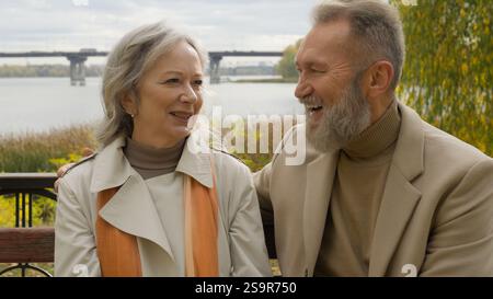 Kaukasisches verheiratetes Paar glückliche ältere Familie Ehemann Ehefrau spricht Lachen auf Bank in der Stadt Herbst Park sorglose Frau Mann Liebe Relax Erholung im Freien Stockfoto