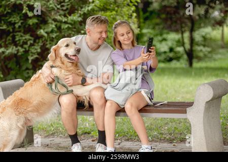 Vater und Tochter machen Ein lustiges Selfie mit Golden Retriever im Park Stockfoto