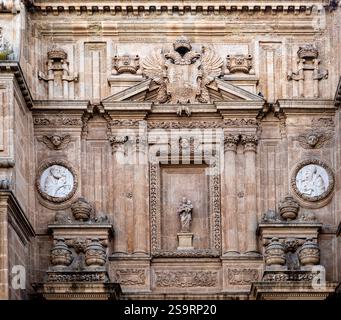 Eine detaillierte architektonische Fassade mit komplizierten Steinschnitzereien, darunter ein Adleremblem, kreisförmige Reliefs von Figuren und verzierte Säulen. Die DE Stockfoto