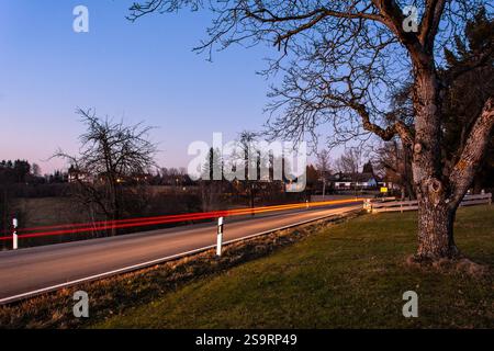 Langzeitaufnahme eines Autos, das nach Sonnenuntergang auf einer Landstraße fährt Stockfoto