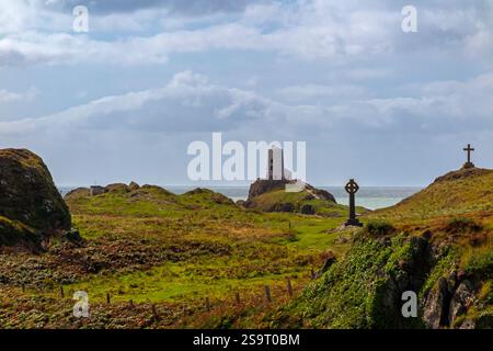 Hügelige Landschaft mit Kreuzen und Leuchtturm auf Ynys Llanddwyn, einer kleinen Insel vor der Küste von Anglesey in Nordwales, Großbritannien. Stockfoto