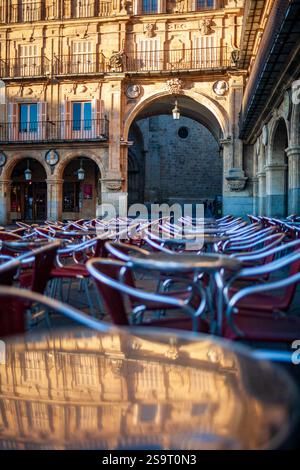 Kaffeetische auf der Plaza Mayor of Salamanca, die das Morgenlicht und architektonische Details reflektieren. Stockfoto