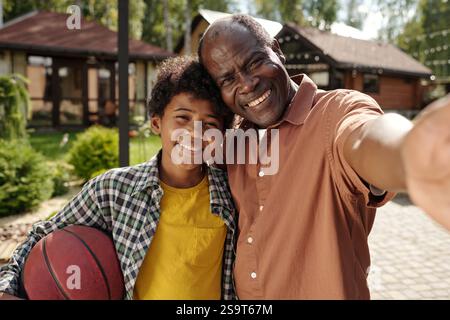 Lächelnder Vater und Sohn halten Basketball vor dem Haus Stockfoto