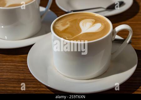 Eine Nahaufnahme einer Tasse Kaffee mit einem herzförmigen Design auf der Oberseite Stockfoto