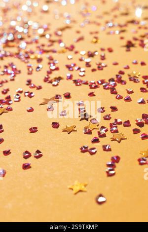 Leuchtende goldene Sterne und Kristalle Konfetti auf gelbem Hintergrund. Selektiver Fokus. Stockfoto
