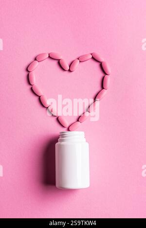 Herzform aus rosa Pillen, minimales Konzept der Herz-Kreislauf-Gesundheit auf rosa Hintergrund, Draufsicht, Kopierraum. Vorlage für weibliche Vitamine und Nahrungsergänzungsmittel. P Stockfoto