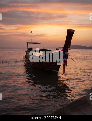 Langboot-Boote, die bei Sonnenuntergang auf dem Wasser schwimmen. Stockfoto