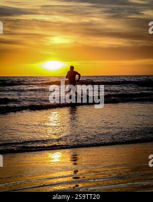 Läufer am Strand bei Sonnenuntergang. Stockfoto