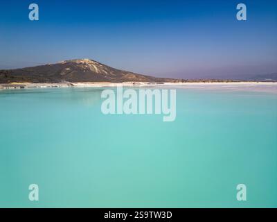 Ein faszinierender türkisfarbener See mit sanftem Himmel und einem ruhigen Horizont. Das ruhige Wasser und die minimalistische Komposition betonen die Harmonie und Stockfoto