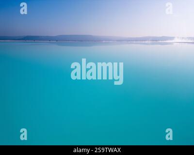 Ein faszinierender türkisfarbener See mit sanftem Himmel und einem ruhigen Horizont. Das ruhige Wasser und die minimalistische Komposition betonen die Harmonie und Stockfoto