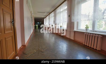 Am letzten Tag vor den Sommerferien durch einen alten Schulflur strömt Sonnenlicht durch die Fenster und wirft Licht und Schatten auf eine Nostalgie Stockfoto