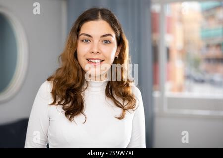 Positive junge Frau, die in die Kamera schaut und lächelt Stockfoto