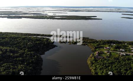 Die Natur am Amur in Russland. Aus der Vogelperspektive werden grüne Flussinseln, die sich verschmelzen und sich windende Gewässer rund um die friedliche Siedlung am Flussufer bilden Stockfoto