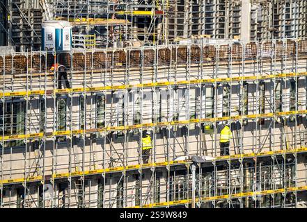Große Baustelle, Neubau umgeben von Gerüsten, Fabrik- und Bürogebäude, Arbeiter am Gerüst während Fassadenarbeiten, Stockfoto