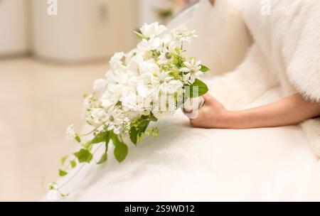Die Frau hält einen Blumenstrauß in der Hand. Der Blumenstrauß liegt in ihrer Hand und wird auf ihrem Schoß platziert Stockfoto