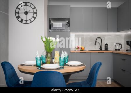Graue Küche und Essbereich mit blauen Stühlen Stockfoto