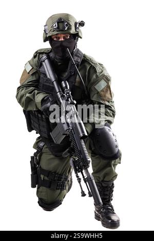 Spezialeinsatzkräfte tragen volle taktische Ausrüstung und sind mit einem Gewehr ausgestattet, was die Essenz moderner militärischer Professionalität im Knien erfasst Stockfoto