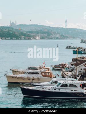 Ruhige Fotografie von Booten, die auf der Bosporusstraße in Istanbul schwimmen, mit der berühmten Skyline der Stadt im Hintergrund. Stockfoto